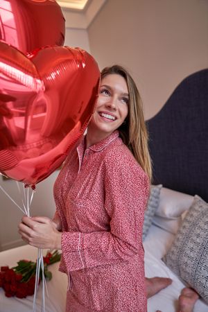 Smiling woman with bunch of red heart shaped balloons