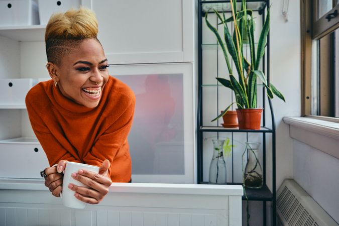 Joyful Black woman with a cup of coffee in a bright modern home