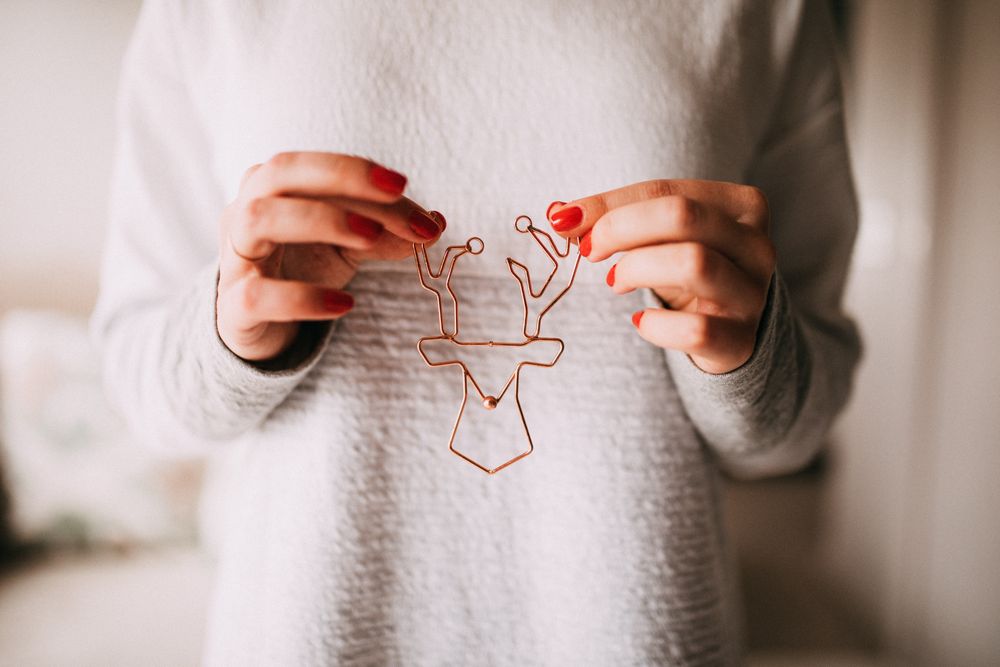 Woman holding a festive brass reindeer ornament