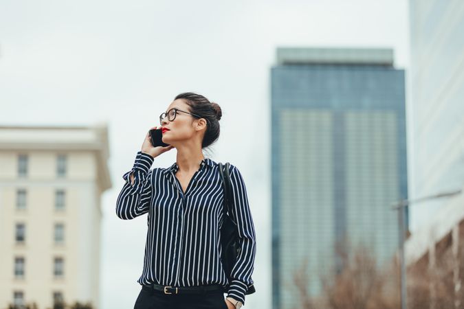 Female business professional walking outside using mobile phone