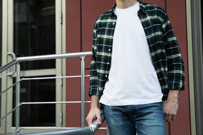 Men in t-shirt and checkered shirt against building, copy space