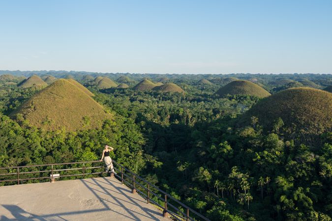 Happy woman standing on observation deck on hill