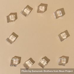 Flat lay of ice cubes on border of beige background with shadows 4Zmg95