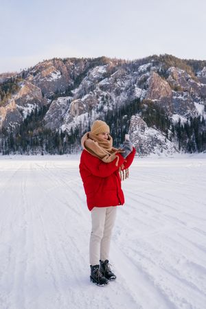 Woman taking picture of snowy mountains with smartphone