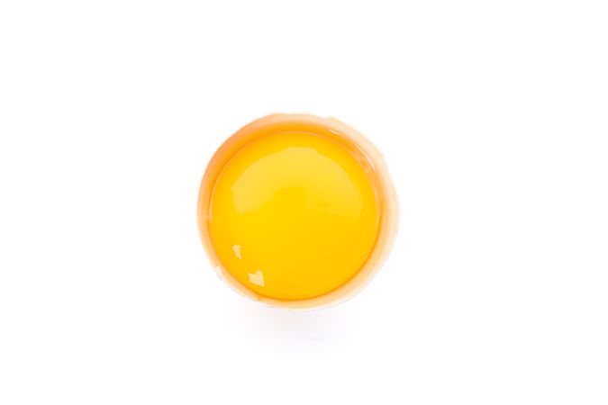 Half broken egg with yolk isolated on blank background, top view