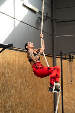 Woman climbing a rope in the gym