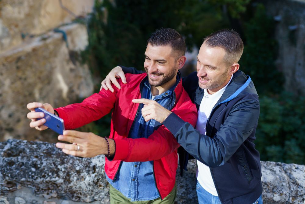 Two smiling men taking selfie outside