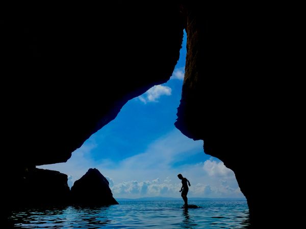 Silhouette of man on sea near cave