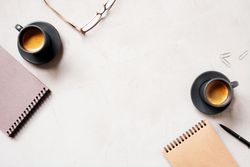 Top view of espresso and notepads on neutral desk