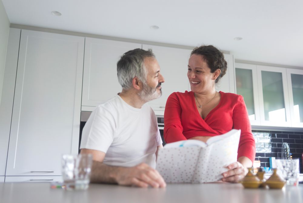 Couple deciding on recipes in bright kitchen