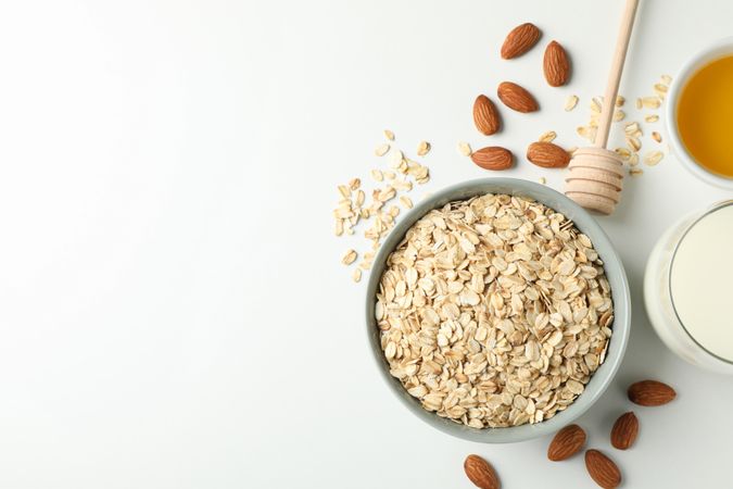 Composition with oatmeal flakes on plain background, top view. Cooking breakfast