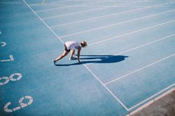 Young woman in the starting position on a track field