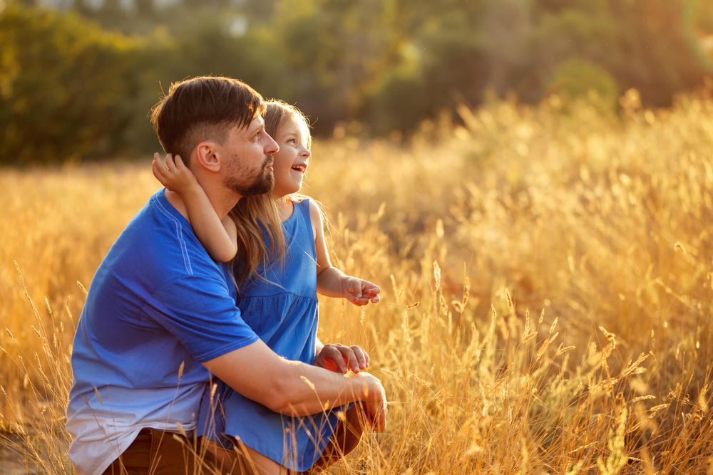 Dad and daughter together in field of long grass