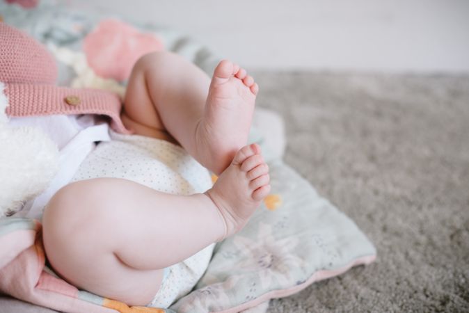 Cute baby lying and playing with plump legs
