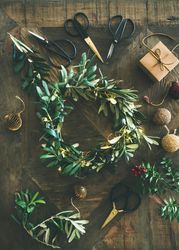 Olive branch festive wreath with scissors and holiday decorations, vertical composition