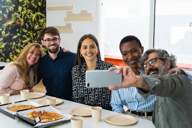 Cheerful multiethnic friends taking selfie during lunch