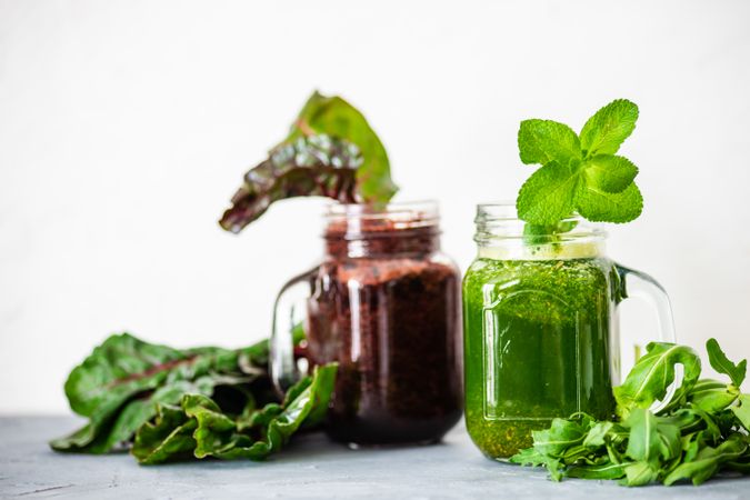 Purple and green smoothie on counter with greens