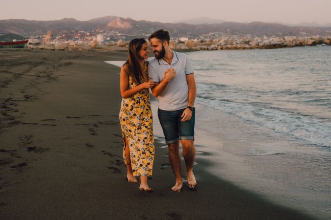 Lovely couple walking holding hands on sandy beach