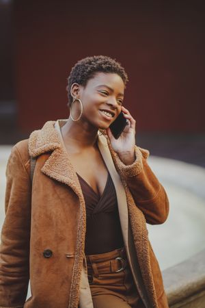 Stylish Black woman talking on smartphone on street