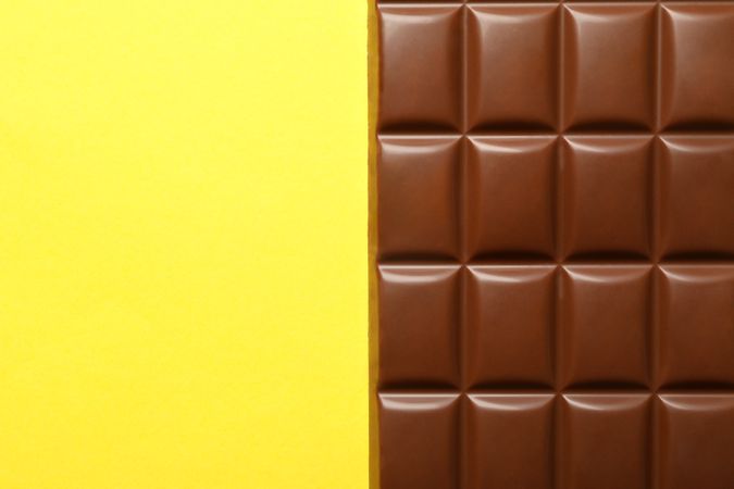 Tasty chocolate bar on yellow background. Sweet food