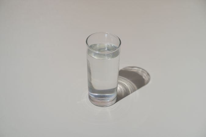 Clear glass of drinking water casting a soft shadow