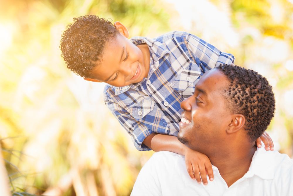 Black Son Smiling At Father Outdoors