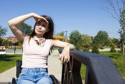 Woman shielding her eyes from the sun with one arm on a bridge