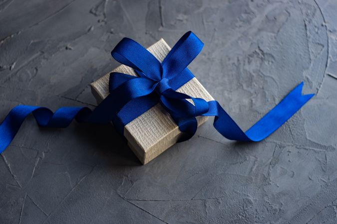 Single gift box with blue ribbon on concrete