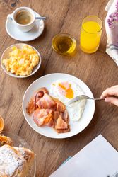 Person reading while eating bacon and eggs at table