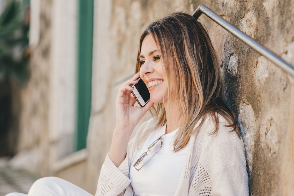 Woman with smartphone sitting on stone steps of stairs