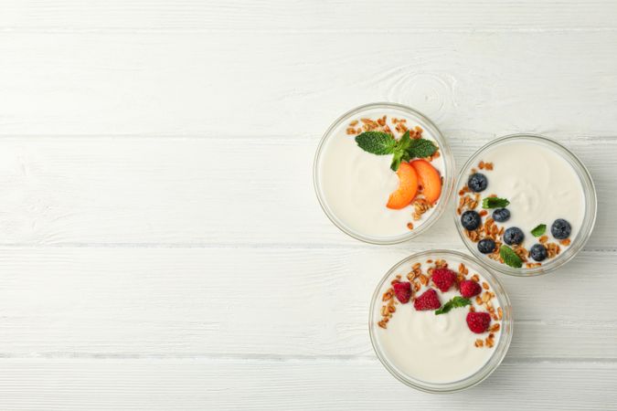 Flat lay composition with yogurt desserts and ingredients on wooden background