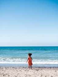 Little girl standing on beach and admiring view