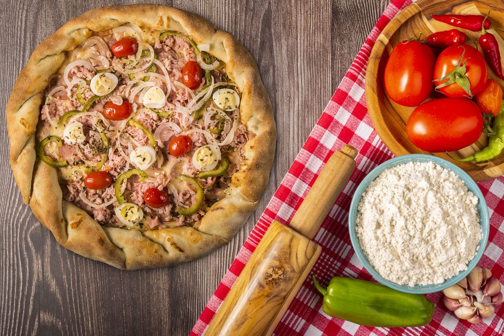 Wooden table with ingredients for pizza.