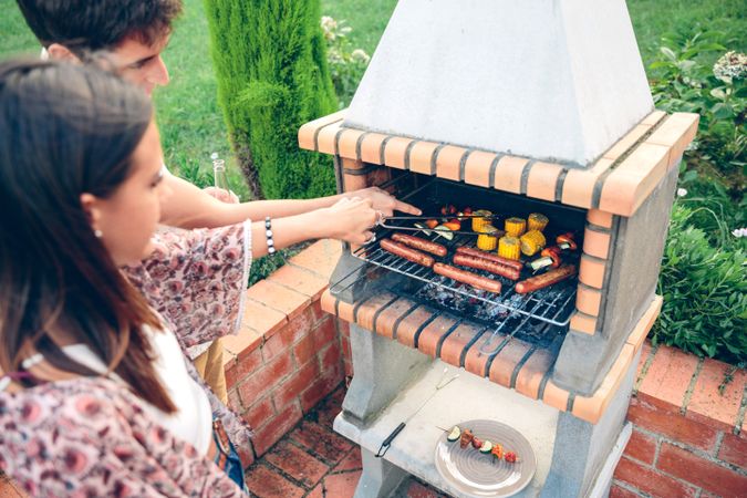 Friends cooking in barbecue at summer party