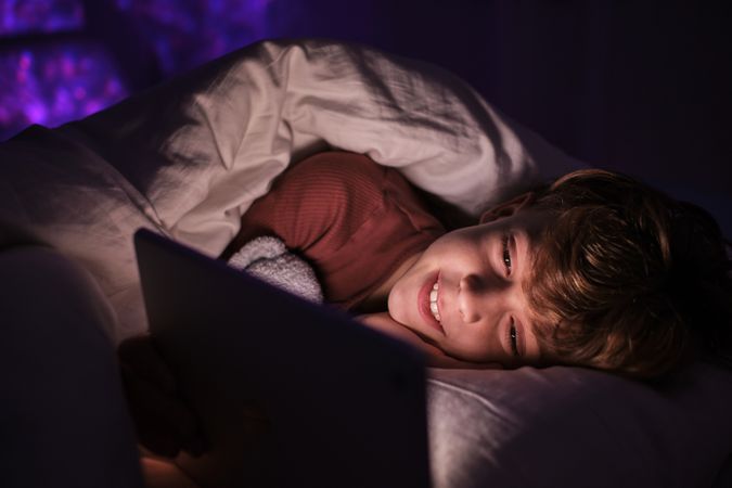 Content boy watching video on tablet at night