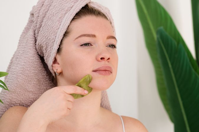 Woman performing facial massage with gua sha