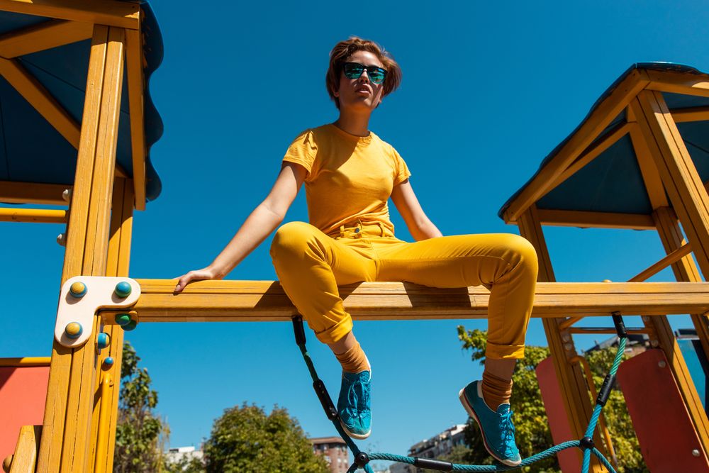Cool stylish young woman in vibrant clothes on playground