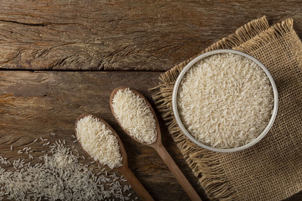 Rice in a ceramic bowl on brown wooden background.