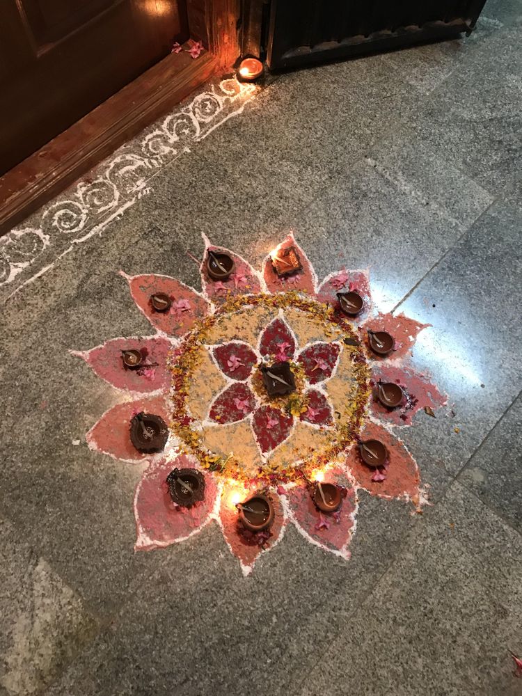 Top view of Rangoli on floor with lit diyas