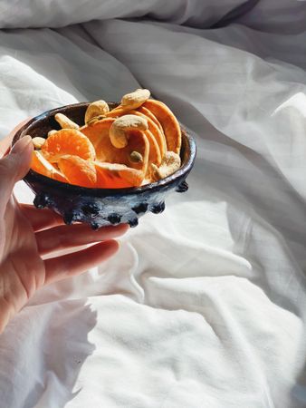Hand holding bowl of oranges and pancakes in morning sun