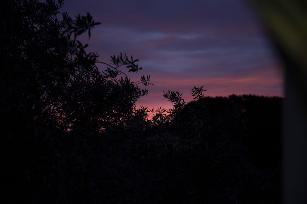 Early morning behind mountains, dark landscape, sunrise sky.