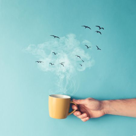 Coffee cup with steam, clouds and birds on blue background