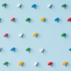 Colorful thumbtacks on blue background