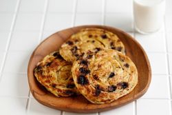 Round plate of sweet raisin cinnamon roti parata or roti canai with milk