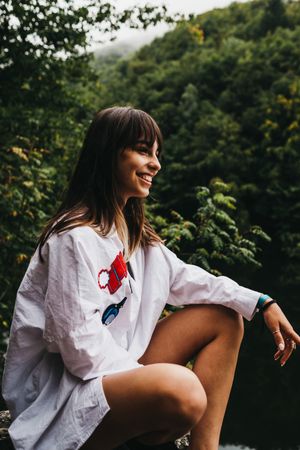 Woman sitting on rock near lake and mountains
