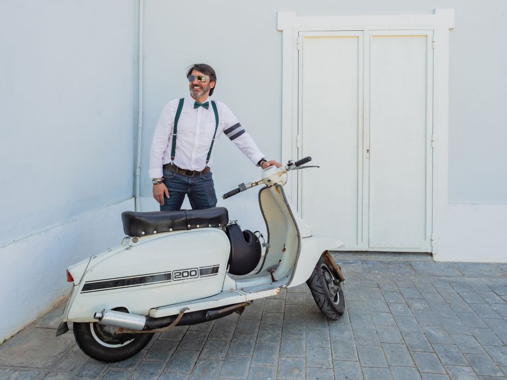 Trendy man sitting on vintage scooter