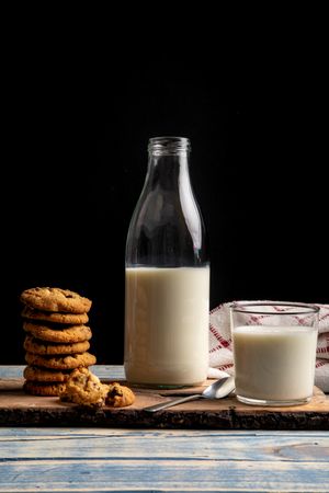 Milk and fresh cookies on board near napkin