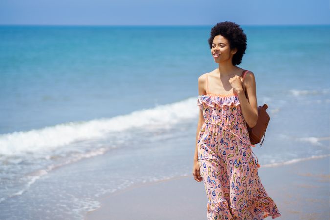 Confident female in maxi dress walking along the coast