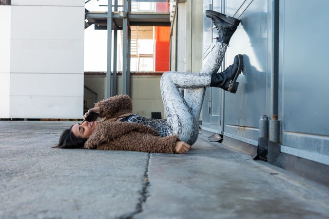 Woman lying on pavement and speaking on phone