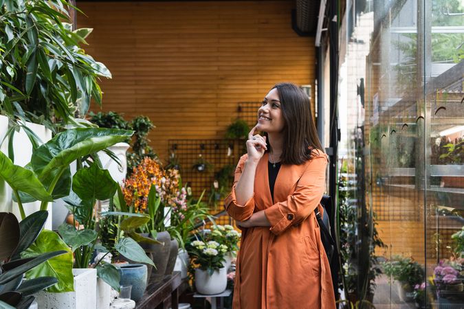 Cheerful woman choosing flowers in garden center